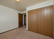 Thumbnail 11 of 23 - a bedroom with a closet and a door to a hallway. Fargo, ND Countryside Apartments.