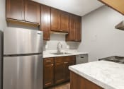 Thumbnail 9 of 14 - St. Louis Park, MN Courtyard Apartments. A kitchen with wooden cabinets and a stainless steel refrigerator