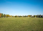 Thumbnail 28 of 31 - A large grassy field with trees in the background. Fargo, ND Stonebridge Apartments