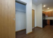 Thumbnail 15 of 23 - a door opens into a kitchen with a black refrigerator and a wood floor. Fargo, ND North Sky Apartments