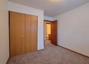 Thumbnail 7 of 10 - a bedroom with a closet and carpeted floors. Fargo, ND Dakota Manor Apartments