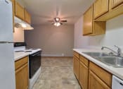 Thumbnail 6 of 10 - a kitchen with white appliances and a dining room in the background with a ceiling fan. Fargo, ND Dakota Manor Apartments