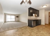Thumbnail 9 of 29 - Anoka, MN Dellwood Estates Apartments. a kitchen and living room with a large window and a ceiling fan