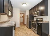 Thumbnail 8 of 29 - Anoka, MN Dellwood Estates Apartments. a kitchen with black cabinets and stainless steel appliances