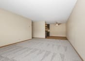 Thumbnail 10 of 29 - Anoka, MN Dellwood Estates Apartments. An empty living room with a ceiling fan and a kitchen in the background