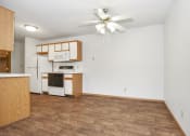 Thumbnail 20 of 29 - an empty living room with a kitchen and a ceiling fan