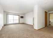 Thumbnail 17 of 29 - an empty living room with a window and a door to a bathroom. Anoka, MN Dellwood Estates