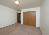 Thumbnail 11 of 12 - a bedroom with carpet and a door to a bedroom. Fargo, ND Dynasty Apartments