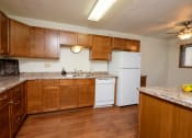 Thumbnail 7 of 12 - a kitchen with wooden cabinets and a white refrigerator. Fargo, ND Dynasty Apartments