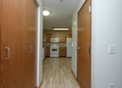 Thumbnail 16 of 21 - a hallway with closet doors and the kitchen in the background. Fargo, ND Crossroads Apartments