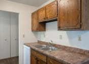 Thumbnail 25 of 42 - a kitchen with a sink and cabinets and a door to a closet.  Eagan, MN Glen Pond Apartments