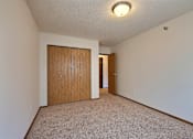 Thumbnail 9 of 28 - A spacious living room with carpet and a door to a bedroom. Fargo, ND Eagle Run Apartments.