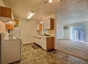 Thumbnail 7 of 28 - A kitchen with white cabinets and white appliances with a living room with a door to a balcony. Fargo, ND Eagle Run Apartments.