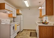 Thumbnail 6 of 28 - A kitchen with white appliances and wooden cabinets and a white refrigerator. Fargo, ND Eagle Run Apartments