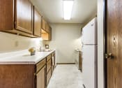Thumbnail 9 of 14 - Bismarck, ND Eagle Sky I Apartments. A kitchen with a white refrigerator freezer next to a white stove top oven