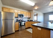 Thumbnail 5 of 12 - a kitchen with stainless steel appliances and wooden cabinets. Fargo, ND East Bridge Apartments