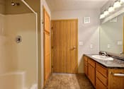 Thumbnail 12 of 12 - a bathroom with a shower and a sink and a mirror. Fargo, ND East Bridge Apartments