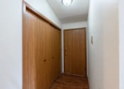 Thumbnail 10 of 19 - an empty hallway with a wooden door and a closet. Fargo, ND Rosegate Apartments