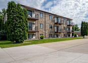 Thumbnail 9 of 10 - A large apartment complex with a parking lot in front. Fargo, ND Hawthorn Apartments