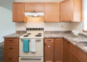 Thumbnail 6 of 13 - a kitchen with wooden cabinets and a stove. Fargo, ND White Ridge Apartments.