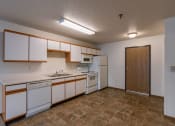 Thumbnail 24 of 49 - an empty kitchen with white appliances and wooden cabinets. Fargo, ND Lake Crest Apartments