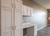 Thumbnail 6 of 25 - a desk with white cabinets and a wood floor. Fargo, ND 29 West Apartments
