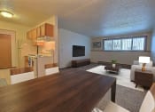 Thumbnail 2 of 10 - a living room and kitchen with a wooden table. Fargo, ND Alden Pines Apartments