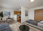 Thumbnail 1 of 7 - Fargo, ND Ashbury Apartments. a bedroom with a bed a table and a chair and a kitchen in the background