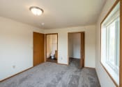 Thumbnail 10 of 13 - Fargo, ND Bayview Apartments. A bedroom with a large window and a door to a bathroom