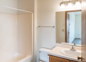 Thumbnail 12 of 13 - Fargo, ND Bayview Apartments. A bathroom with a bathtub sink and mirror