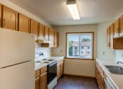 Thumbnail 8 of 13 - Fargo, ND Bayview Apartments. A kitchen with white appliances and wooden cabinets