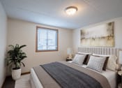 Thumbnail 5 of 15 - a bedroom with a bed and a potted plant and a window. Fargo, ND Bella Vista Apartments