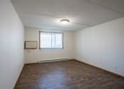 Thumbnail 11 of 15 - the living room of an empty apartment with wood flooring and a window. Fargo, ND Bella Vista Apartments