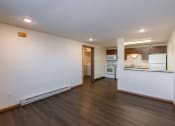 Thumbnail 5 of 9 - an empty living room and kitchen with white walls and wood flooring. Fargo, ND Berkshire Apartments