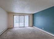 Thumbnail 5 of 25 - an empty living room with a large window and a blue wall. Fargo, ND Betty Ann Apartments