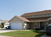 Thumbnail 2 of 4 - a tan house with a white garage door and a lawn. Fargo, ND Bluestem Townhome
