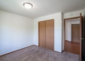 Thumbnail 9 of 26 - a bedroom with a door to a closet and a carpeted floor. Fargo, ND Briar Pointe Apartments