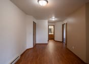 Thumbnail 7 of 26 - an empty living room and hallway with wood floors and white walls. Fargo, ND Briar Pointe Apartments