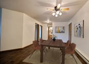 Thumbnail 6 of 33 - Fargo, ND Brownstone Apartments. a dining room with a wooden table and chairs and a ceiling fan
