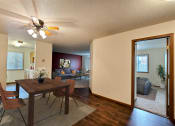 Thumbnail 5 of 33 - Fargo, ND Brownstone Apartments. a living room and dining room with a wooden table and chairs and a ceiling fan