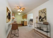 Thumbnail 3 of 17 - Fargo, ND Cambridge Apartments a living room with a ceiling fan and a desk with a chair