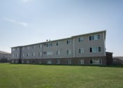 Thumbnail 17 of 17 - Fargo, ND Cambridge Apartments. A large apartment building with a green lawn in front of it