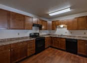 Thumbnail 11 of 41 - a kitchen with wooden cabinets and black appliances. Fargo, ND Carlton Place Apartments