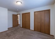 Thumbnail 16 of 41 - an empty room with three doors and a carpeted floor. Fargo, ND Carlton Place Apartments