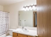Thumbnail 15 of 44 - a bathroom with a sink and a mirror and a shower. Fargo, ND Country Edge Apartments