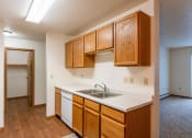 Thumbnail 11 of 44 - an empty kitchen with a sink and wooden cabinets. Fargo, ND Country Edge Apartments