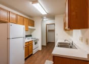 Thumbnail 10 of 44 - a kitchen with white appliances and wooden cabinets and a refrigerator. Fargo, ND Country Edge Apartments