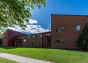 Thumbnail 1 of 16 - an exterior view of a brick apartment building with green grass. Fargo, ND Crescent Park Apartments.
