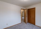 Thumbnail 12 of 16 - a bedroom with a closet and a door to a hallway. Fargo, ND Crescent Park Apartments