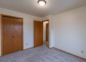 Thumbnail 10 of 16 - a bedroom with carpet and a door to a hallway. Fargo, ND Crescent Park Apartments